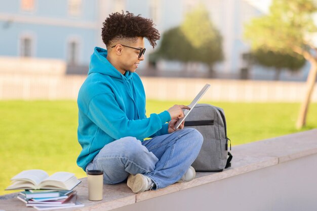 Estudante preto navegando e aprendendo via tablet digital ao ar livre