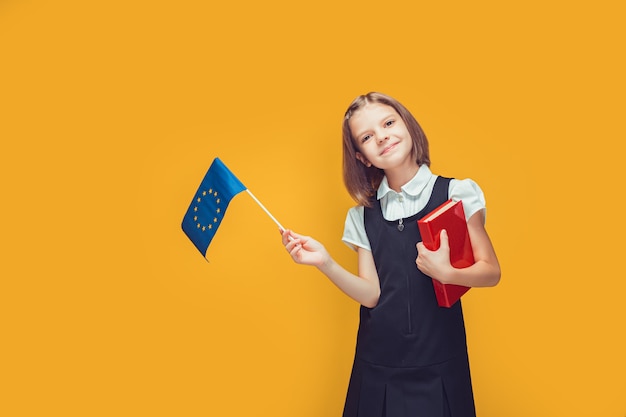 Estudante segurando uma pequena bandeira da união europeia e um livro nas mãos, educação no conceito de europa