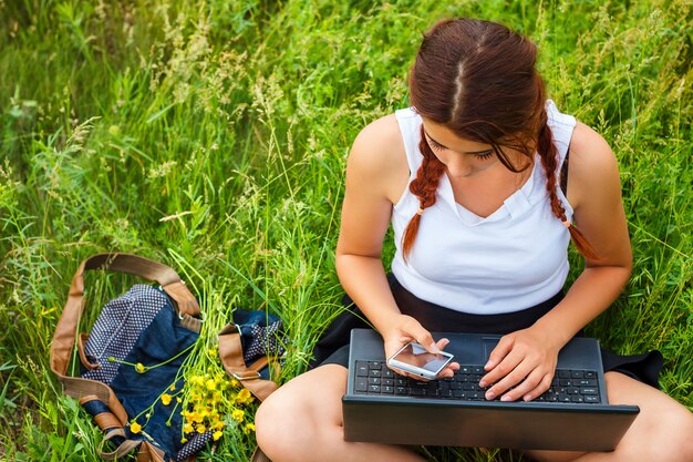 Estudante sentado com um laptop na grama, vista superior