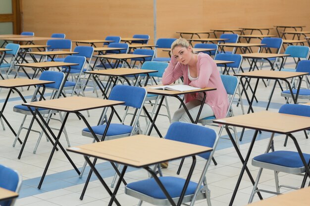 Foto estudante sentado na mesa no salão de exame vazio