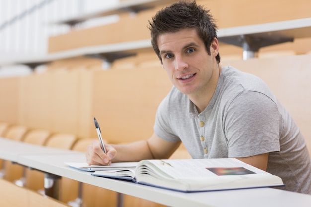 Estudante sentado na mesa, sorrindo