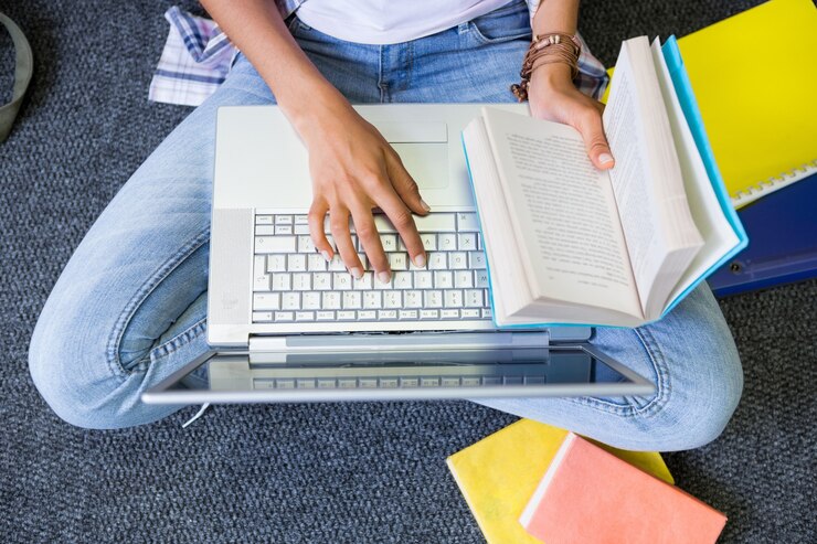 Foto estudante sentado no chão em biblioteca usando laptop
