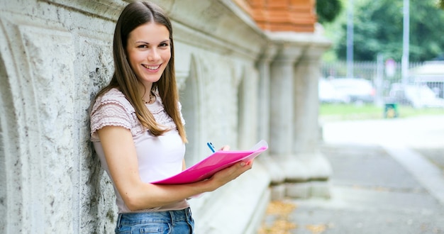 Foto estudante sorridente ao ar livre, lendo um livro