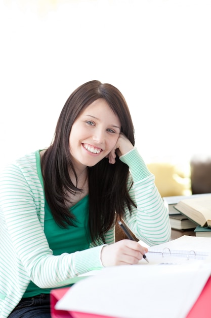 Estudante sorridente e morena fazendo o dever de casa