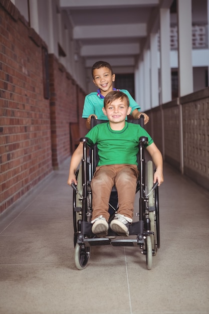 Estudante sorridente em cadeira de rodas e amigo empurrando