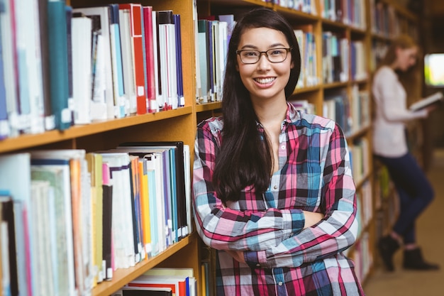 Estudante sorridente encostado pra estantes de livros