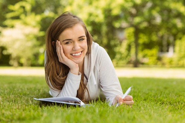 Estudante sorridente estudando e escrevendo no bloco de notas