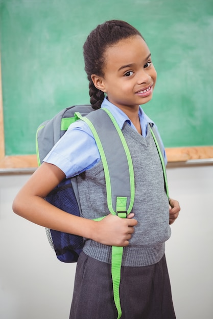 Estudante sorrindo e vestindo uma bolsa de escola