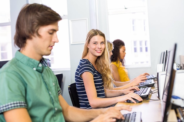 Estudante sorrindo na câmera na classe de computador