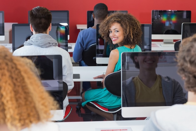 Estudante sorrindo para a câmera na aula de informática