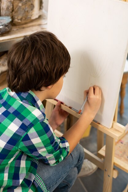 Foto estudante talentoso de cabelos escuros desenhando na escola de arte