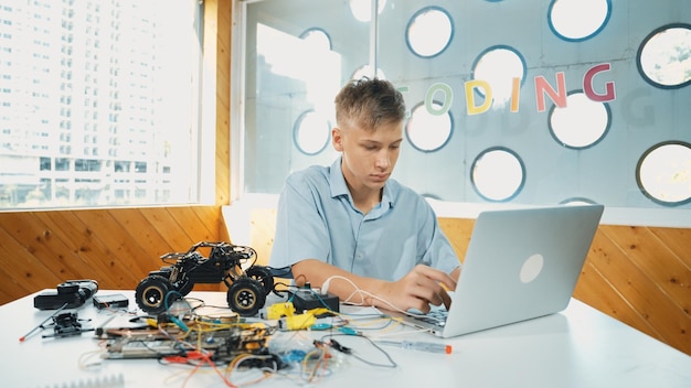 Foto estudante trabalhando em laptop enquanto analisa edificação de construção de modelo de carro