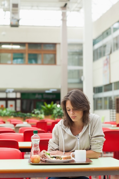 Estudante triste no refeitório com bandeja de comida