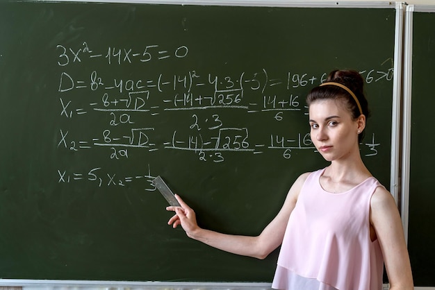 Estudante universitária escrevendo no quadro-negro completando o conceito de educação de equações matemáticas