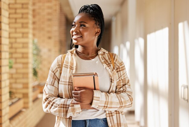 Foto estudante universitária negra e pensando no futuro com livros enquanto caminhava no campus ou na universidade jovens da geração z felizes com o aprendizado educacional e a escolha de estudar no prédio da escola