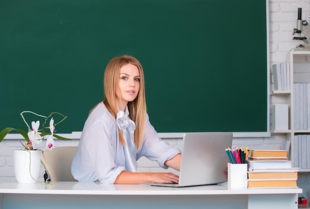 Estudante universitária trabalhando em um laptop em sala de aula se preparando para uma estudante adolescente de exame