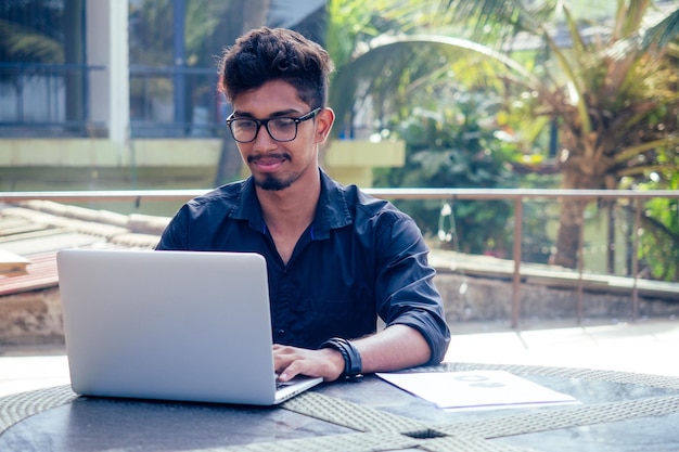 Estudante universitário asiático indiano estudando freelancer trabalhando com um laptop na praia verão café freelance e empresário de trabalho remoto na varanda varanda