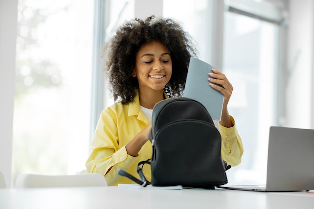 Estudante universitário colocando livros na mochila depois de estudar na universidade