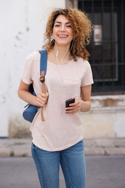 Foto estudante universitário feminino andando lá fora com o telefone móvel e fones de ouvido