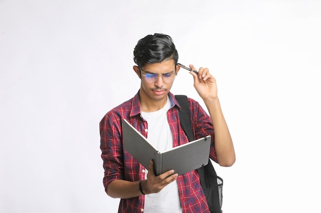 Estudante universitário indiano em pé com o saco e lendo os produtos lácteos sobre fundo branco.