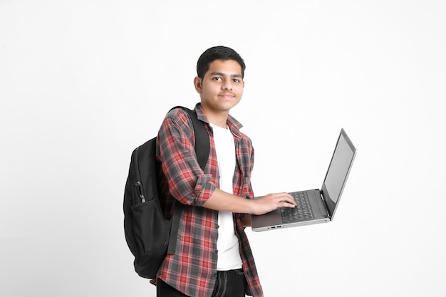 Estudante universitário indiano usando laptop na parede branca