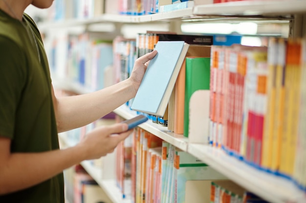 Estudante universitário tirando livro da prateleira