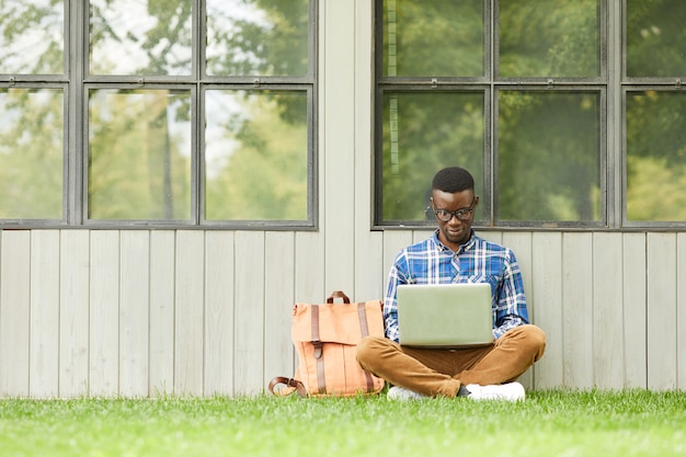 Estudante universitário usando laptop ao ar livre