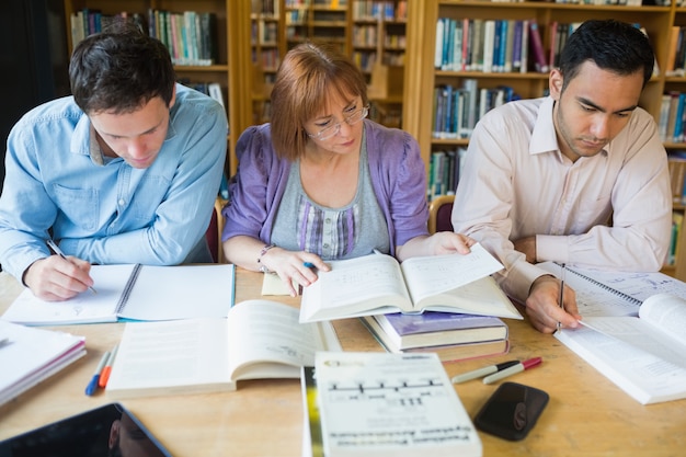 Estudantes adultos estudando juntos na biblioteca