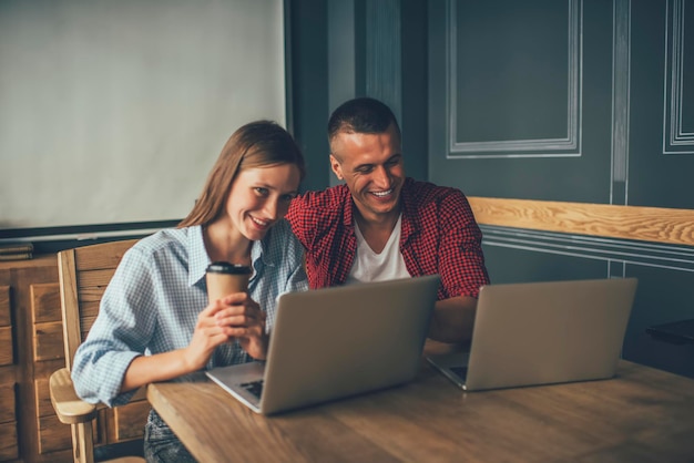 Estudantes alegres usando laptops e navegando na internet