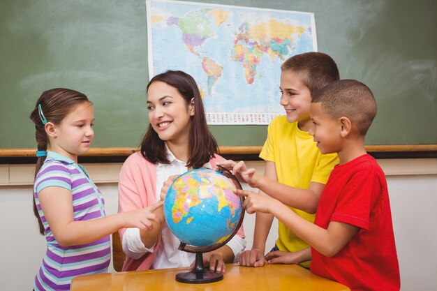 Estudantes apontando para lugares em um globo