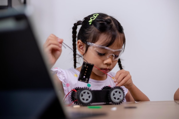 Estudantes asiáticos aprendem em casa codificando carros robôs e cabos de placas eletrônicas em STEM STEAM matemática engenharia ciência tecnologia código de computador em robótica para conceitos infantis