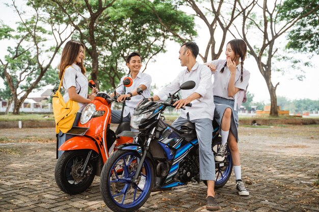 Foto estudantes asiáticos de ensino médio conversando sentados em uma motocicleta