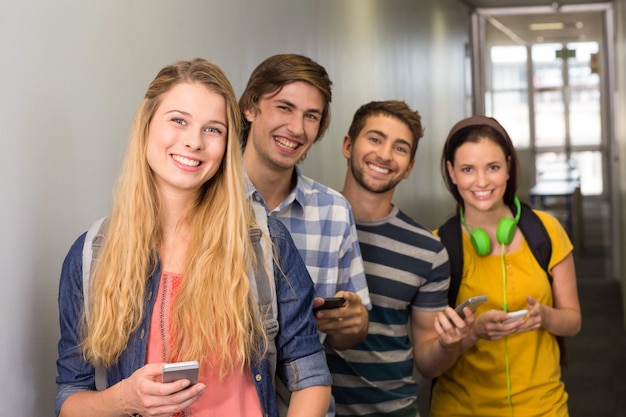 Estudantes com celulares no corredor da faculdade