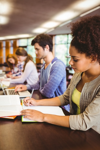 Foto estudantes concentrados sentados em uma linha de escrita