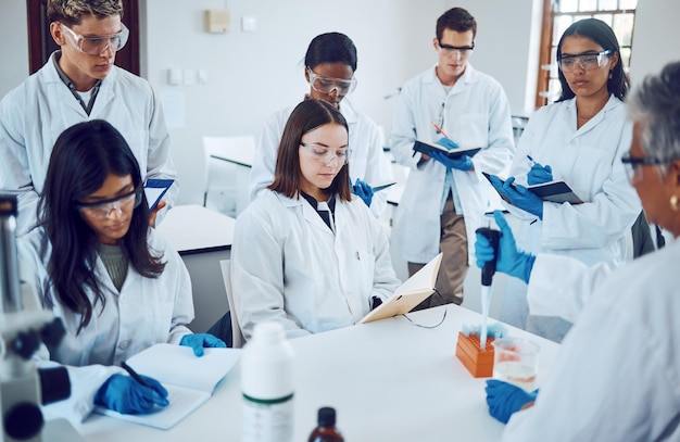 Estudantes de ciências e educação em um laboratório médico escrevendo notas durante a palestra ou aula do cientista com mentor ou professor Médicos e mulheres para treinamento e aprendizado na aula de química