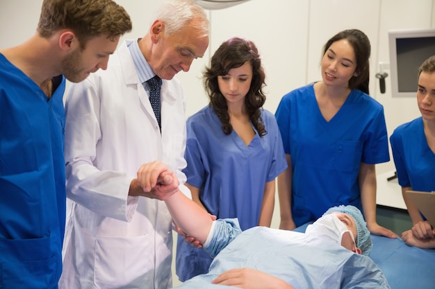 Estudantes de medicina e professor checando pulso do aluno