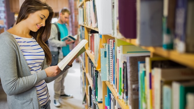 Estudantes de pé na estante de livros na biblioteca