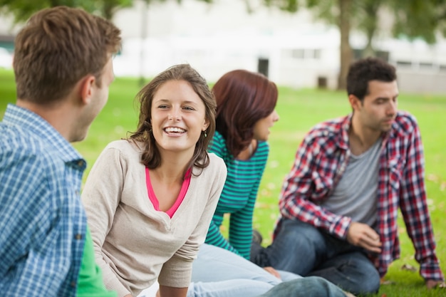 Estudantes de riso casual sentados na grama conversando