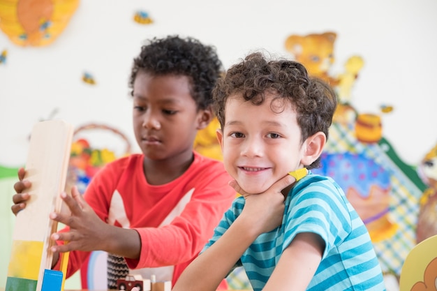 Estudantes do jardim de infância sorriem quando jogam brinquedos na sala de jogos na pré-escola internacional