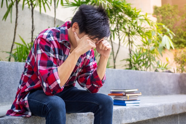 Estudantes do sexo masculino asiáticos sentados preocupados estressados, com os resultados dos exames reprovados.