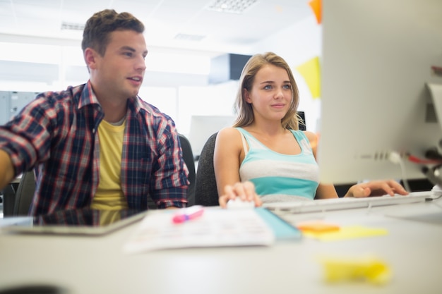 Estudantes felizes que trabalham juntos na sala de informática