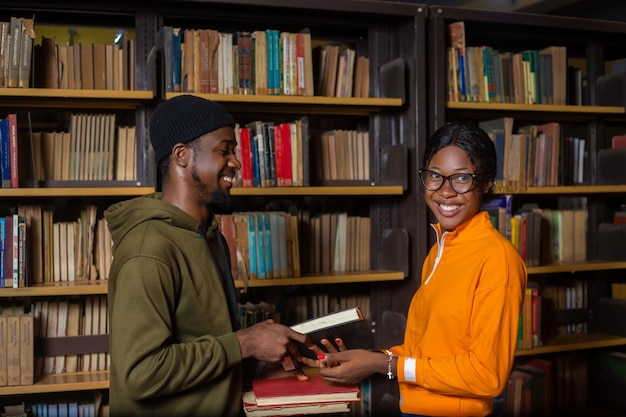 Estudantes felizes segurando um livro em uma biblioteca