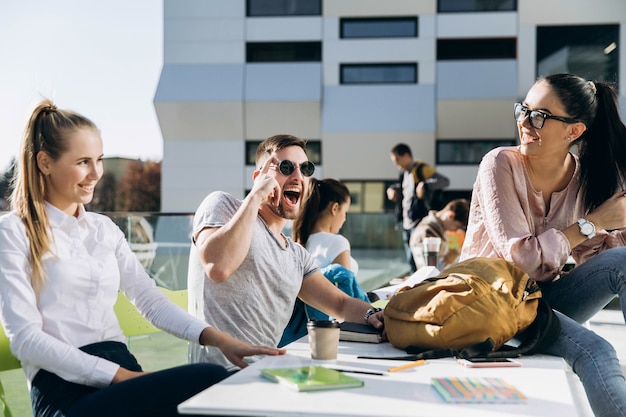 Estudantes felizes trabalham e estudam à mesa no ar fresco