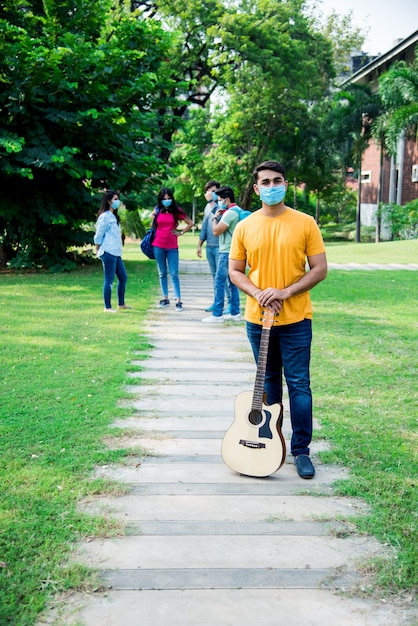 Estudantes indianos asiáticos usam máscara facial e seguem normas de distanciamento social no campus da faculdade ou universidade após o desbloqueio da pandemia corona, foco em um aluno