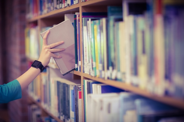 Estudantes mão com smartwatch picking book from bookshelf