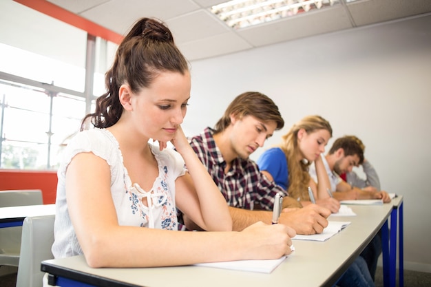 Estudantes que escrevem notas na sala de aula