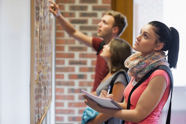 Foto estudantes que olham no quadro de avisos