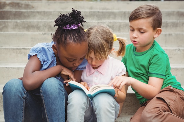 Estudantes sentados em passos e lendo um livro