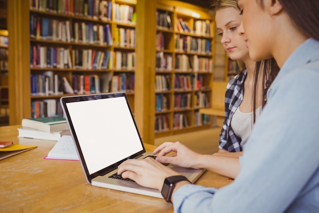 Estudantes sérios usando o laptop na biblioteca