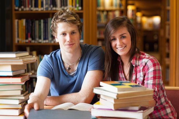 Estudantes sorridentes cercados por livros